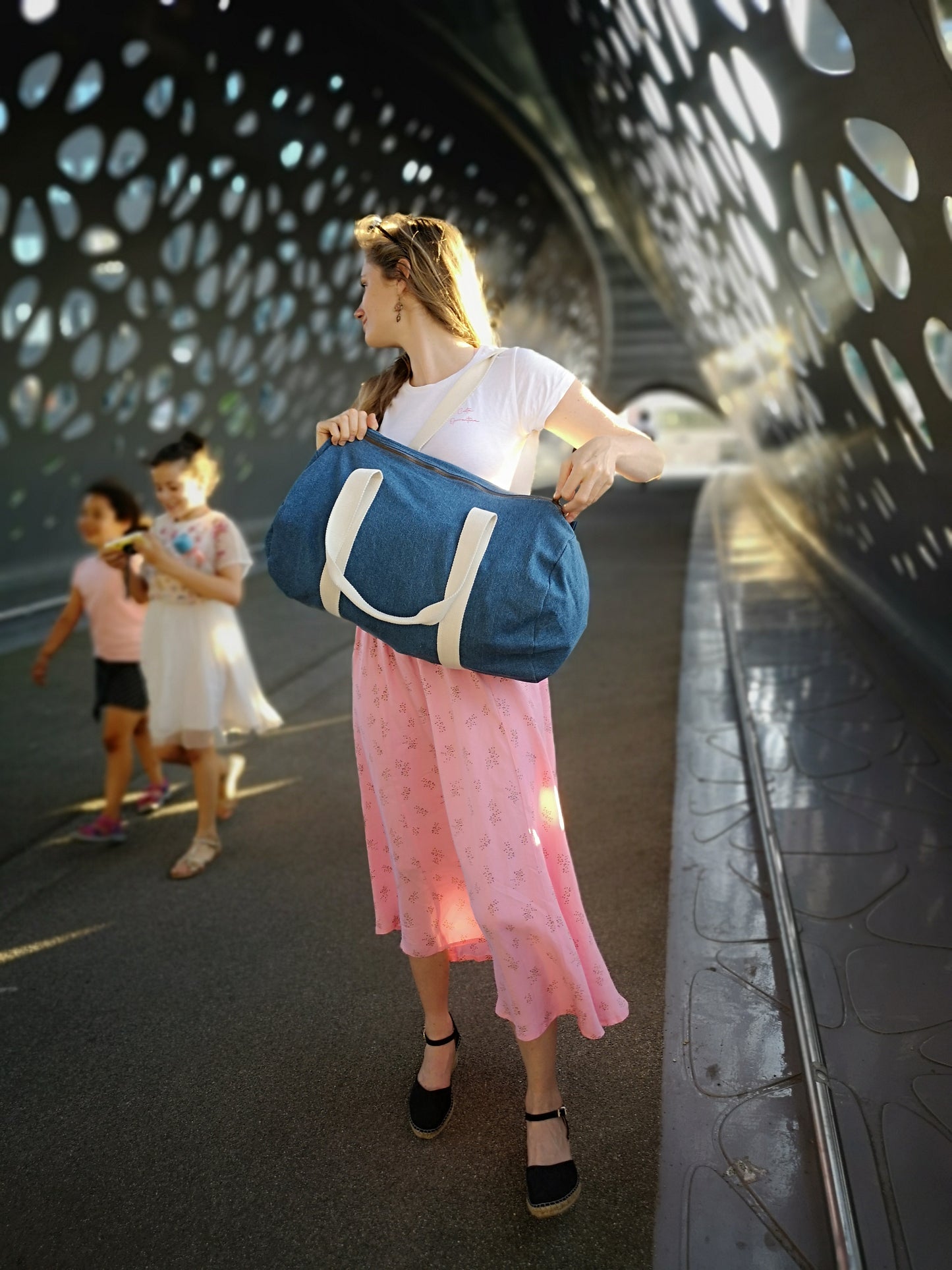 Een vrouw op een brug te Antwerpen met een uniek te personaliseren weekendtas of luiertas en haar 2 kindjes op de achtergrond