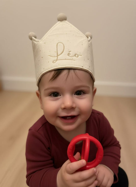 Baby met gepersonaliseerde verjaardagskroon met pompom en gouden naam borduring