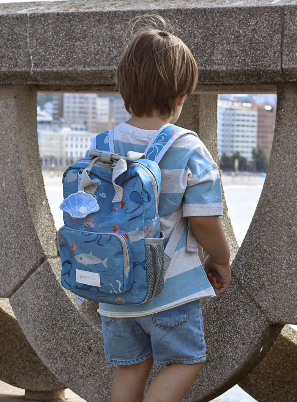 Jongetje met een gepersonaliseerde peuter of kinder rugzak met zee thema print van het merk Play and Store geborduurd op naam