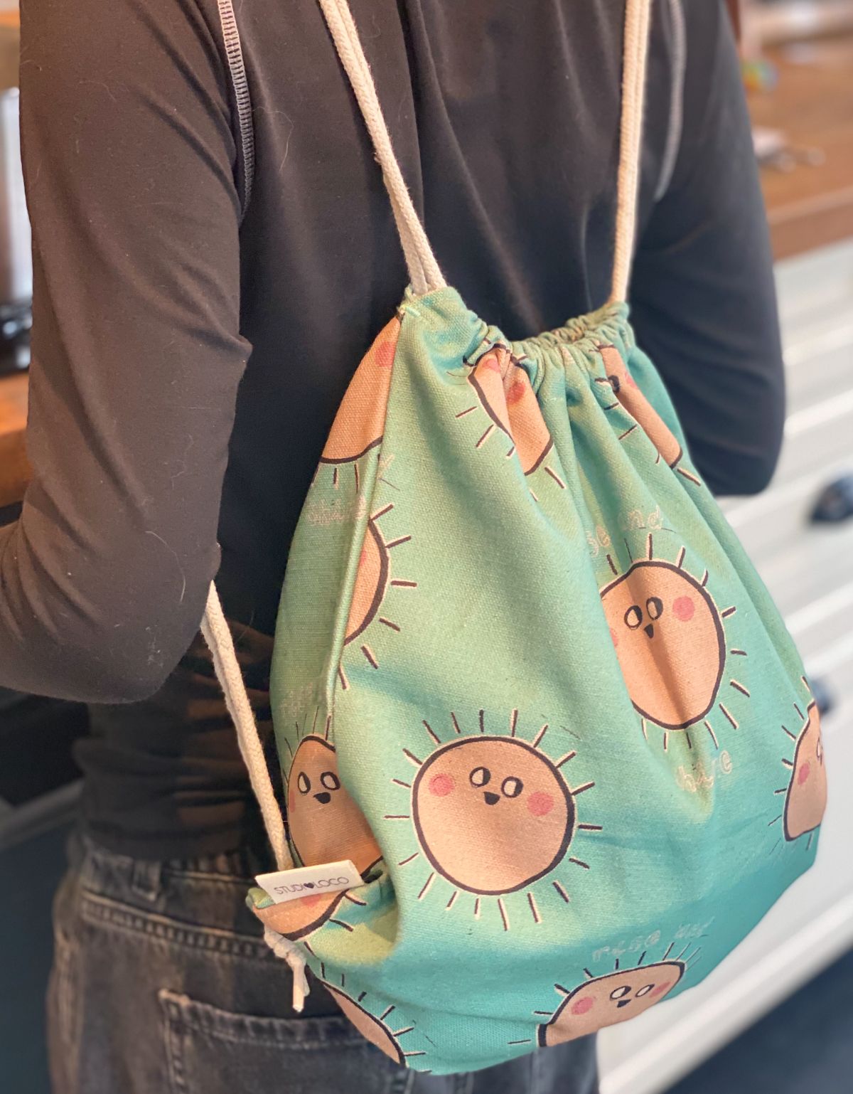 Kind met een gepersonaliseerde turnzak met speelse zonnige print van het merk Studio Loco geborduurd op naam