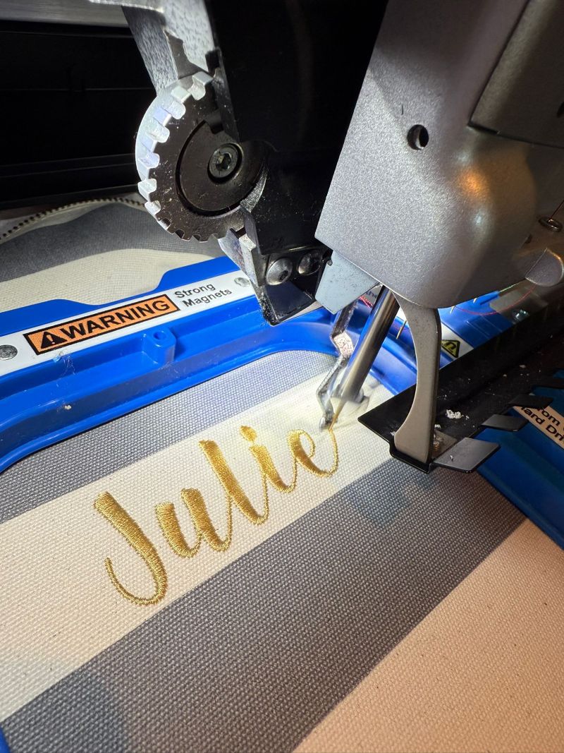 Stijlvol geborduurde naam in het goud op een weekendtas met strepen patroon