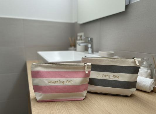 Stijlvolle toilettassen met geborduurde tekst in het goud en roze of grijze strepen